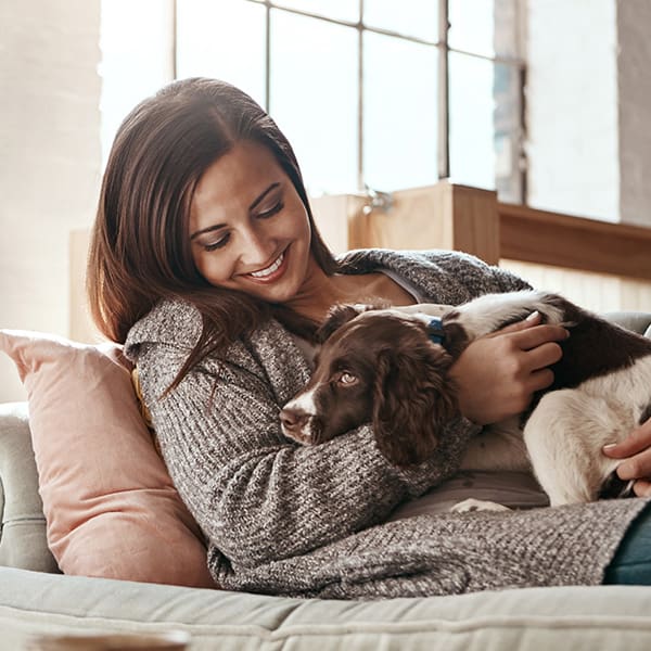 Woman Laying With Dog On Her On A Couch